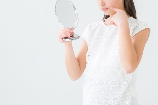 口もとを鏡でみる女性 口もとを鏡でみる女性
